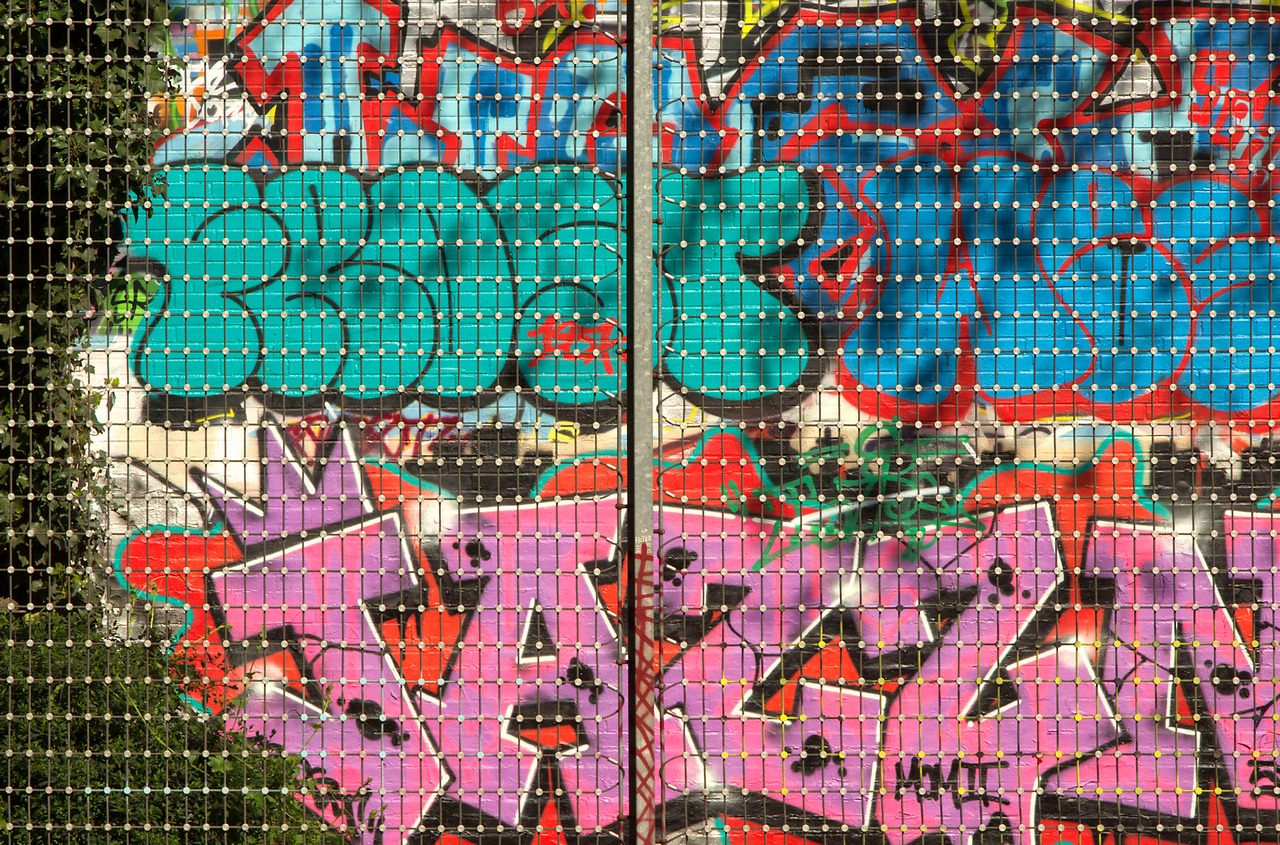 Grafitti hinter Zaun